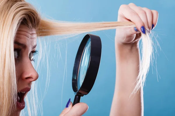 Femme regardant les cheveux à travers la loupe — Photo