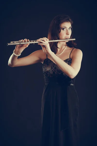 Woman playing transverse flute on black. — Stock Photo, Image