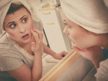 Bir kadın aynadaki yansımasına bakıyor.