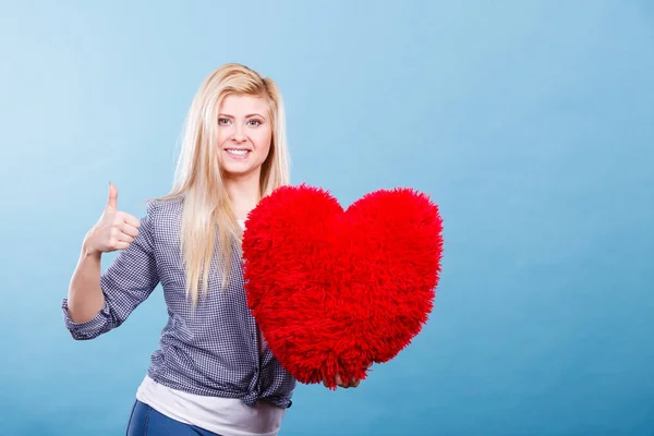 Kırmızı yastık kalp şeklinde tutan mutlu kadın — Stok fotoğraf