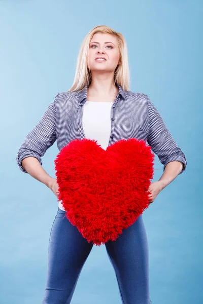 Mulher feliz segurando travesseiro vermelho em forma de coração — Fotografia de Stock