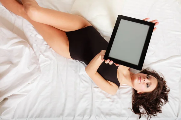 Sexy chica perezosa acostada con tableta touchpad en la cama — Foto de Stock