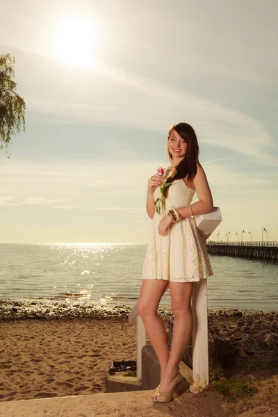 Femme debout sur la plage tenant tulipe rose — Photo