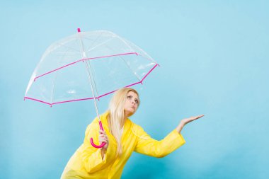 Hava kontrol şemsiye tutan yağmurluk giyen kadın