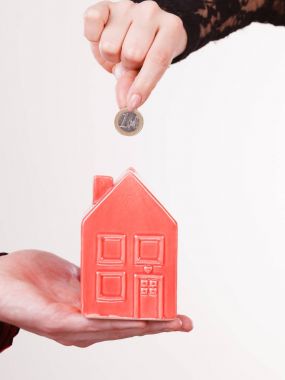 İnsanlar elleriyle küçük ev ve gümüş sikke.