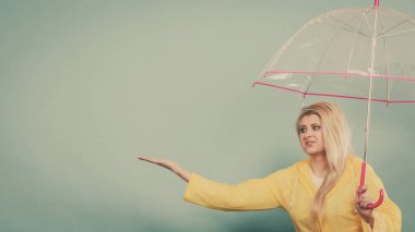 Hava kontrol şemsiye tutan yağmurluk giyen kadın