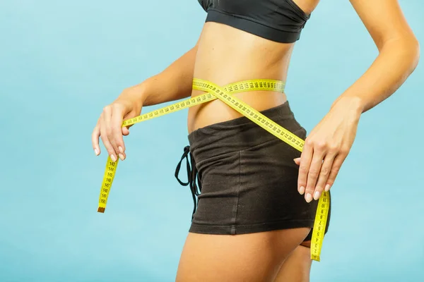 Fitness girl measuring her waistline — Stock Photo, Image