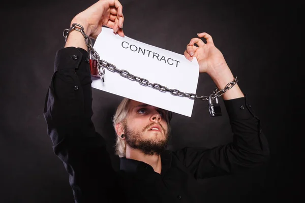 Man with chained hands holding contract