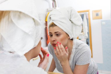 Bir kadın aynadaki yansımasına bakıyor.