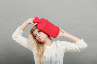 Kırmızı sıcak su şişesi üzerinde kafa tutan kadın