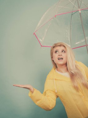 Hava kontrol şemsiye tutan yağmurluk giyen kadın