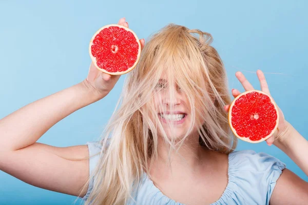 Женщина, держащая красный грейпфрут с безумными ветреными волосами — стоковое фото