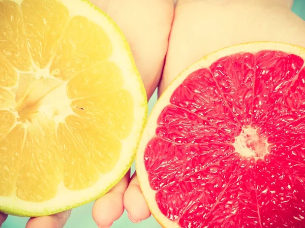 Helften van gele rode grapefruit citrusvruchten in menselijke handen — Stockfoto