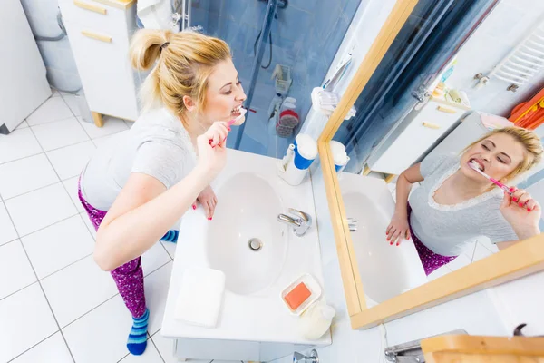 Mulher escovando os dentes de limpeza no banheiro — Fotografia de Stock