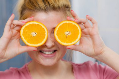 Turuncu tutan yüzünde jel maskesi olan kadın