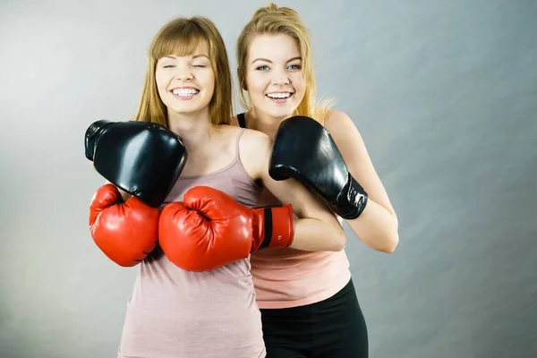 Two women friends wearing boxing gloves