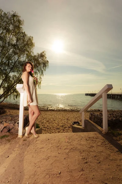 Mulher de pé na praia segurando tulipa rosa — Fotografia de Stock