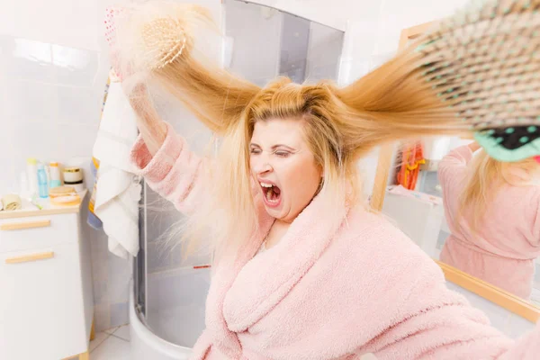 Zszokowana kobieta ubrana szlafrok szczotkowanie jej włosy — Zdjęcie stockowe