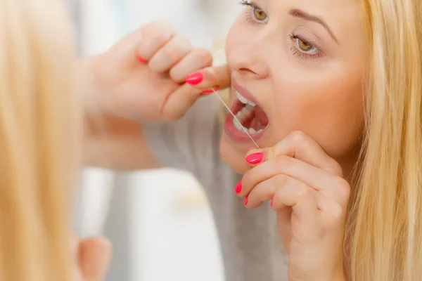 Mulher limpando os dentes usando fio dental — Fotografia de Stock