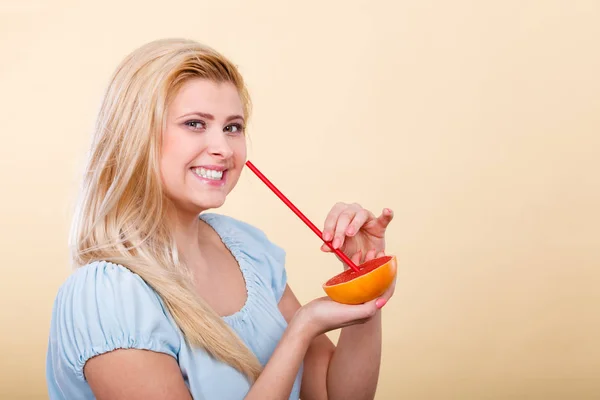Женщина пьет сок из фруктов, красный грейпфрут — стоковое фото