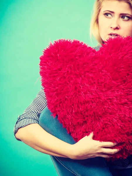 Donna triste che tiene il cuscino rosso a forma di cuore Fotografia Stock