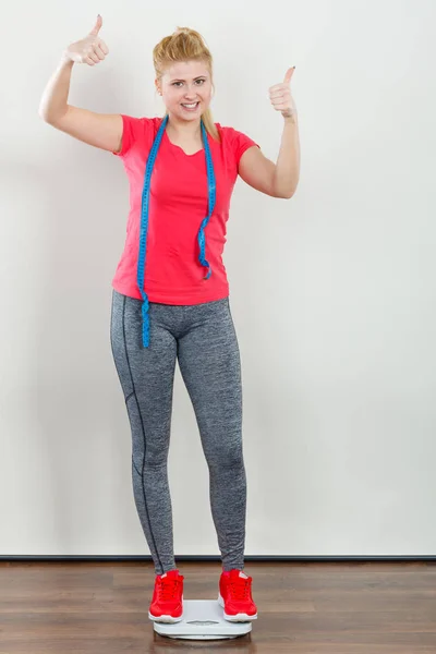 Woman wearing sportswear standing on weight machine — Stock Photo, Image