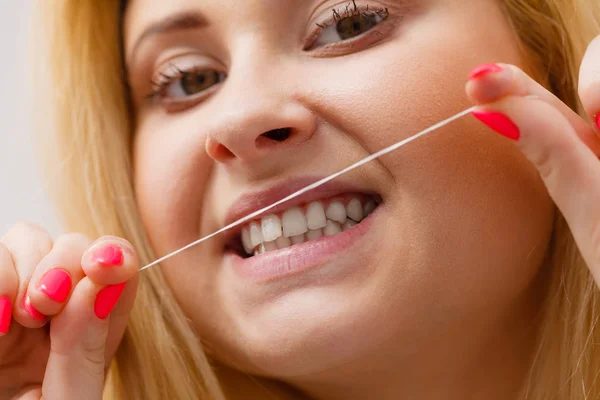 Mulher limpando os dentes usando fio dental — Fotografia de Stock