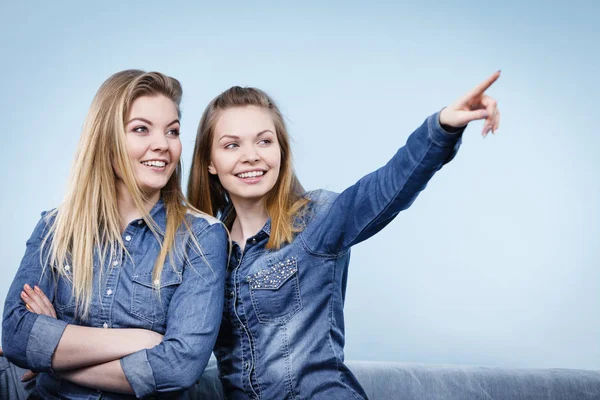 Två glada kvinnor vänner bära jeans outfit poitning — Stockfoto