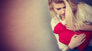 Holding sıcak su şişesi kadının duygu mide krampları