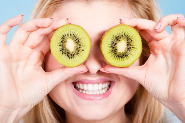 Woman holding green kiwi fruit like eyeglasses — Stock Photo, Image