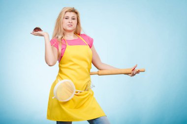 Tutan cupcake, oklava, kevgir önlük giyen kadın