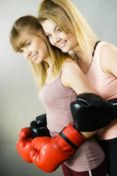 Two women friends wearing boxing gloves