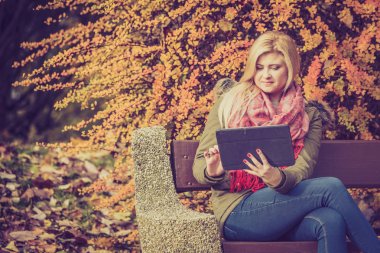 Tablet kullanarak parkta bankta oturmuş rahatlatıcı kadın