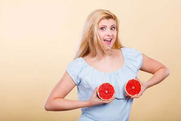 Женщина с красным грейпфрутом на груди — стоковое фото