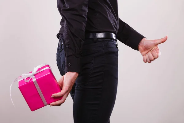 Hombre ocultando caja de regalo rosa con cinta detrás de la espalda — Foto de Stock