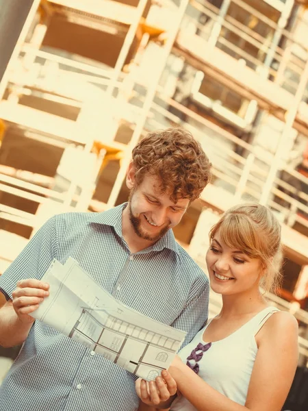 Pareja en frente de casa nueva con proyecto de anteproyecto — Foto de Stock