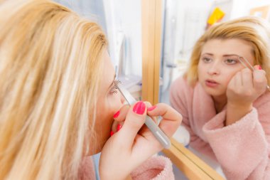 Kaşlarını cımbızla temizleyen kadın.