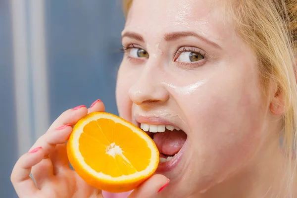 Mulher com máscara de gel no rosto segurando laranja — Fotografia de Stock