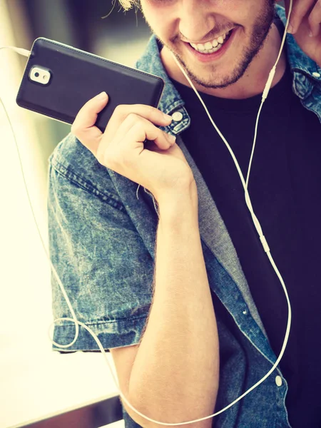 Hipster man standing with earphones talking on phone — Stock Photo, Image