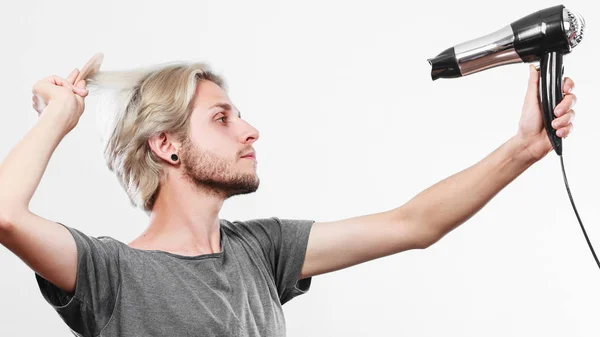 Joven hombre secando el cabello con secador de pelo — Foto de Stock