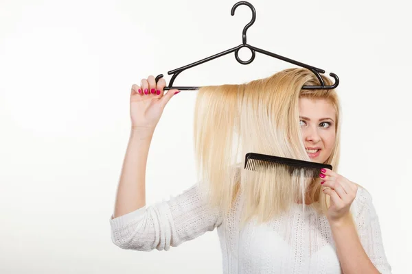 Mulher loira segurando o cabelo no cabide de roupas — Fotografia de Stock