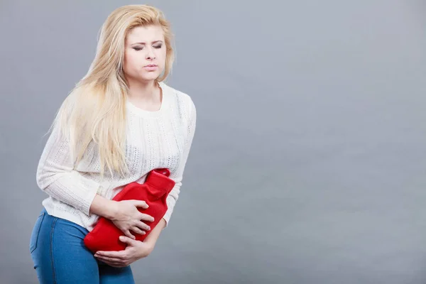 Femme sentiment crampes d'estomac tenant une bouteille d'eau chaude — Photo