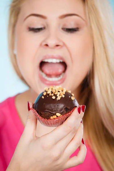 Kvinna som håller choklad cupcake på väg att bita Stockfoto