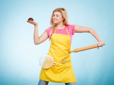 Tutan cupcake, oklava, kevgir önlük giyen kadın