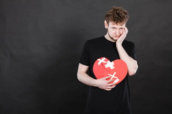 Muito triste jovem segurando coração partido — Fotografia de Stock