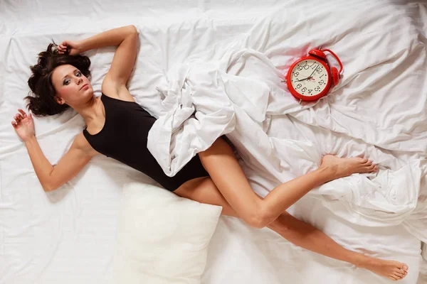 Sexy lui meisje met rode wekker op bed liggen — Stockfoto
