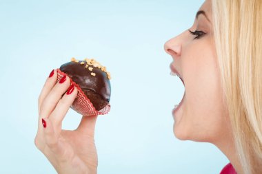 Çikolatalı kek tutan kadın ısırmak üzere.