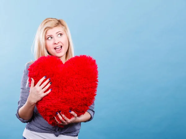 Kırmızı yastık kalp şeklinde tutan mutlu kadın — Stok fotoğraf