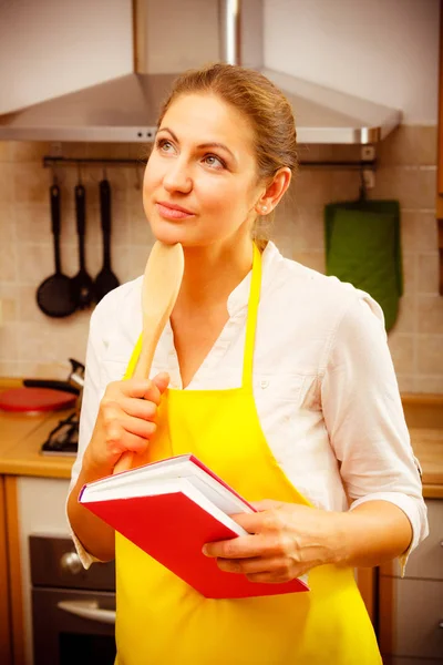 Mulher dona de casa com livro de receitas na cozinha . — Fotografia de Stock