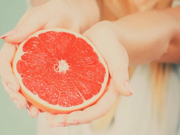 Half of red grapefruit citrus fruit in human hands